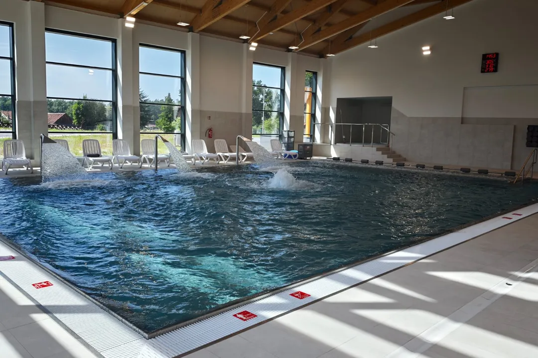 Basen rehabilitacyjny ze stanowiskami hydromasażu w hali z drewnianym stropem
